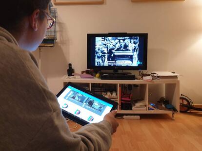 Una joven consulta la tableta con facilidades para compartir contenidos mientras ve la televisión.