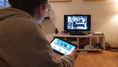 Una joven consulta la tableta con facilidades para compartir contenidos mientras ve la televisión.