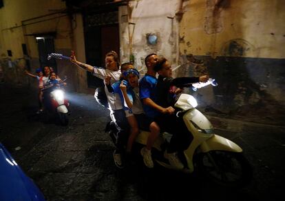 Cinco aficionados del Nápoles celebran a lomos de una moto el título de su equipo por las calles de la ciudad italiana. 