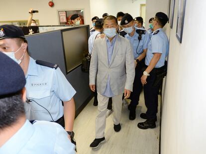 El empresario Jimmy Lai, en el centro, escoltado por la policía en la redacción de 'Apple Daily', este lunes, en Hong Kong.