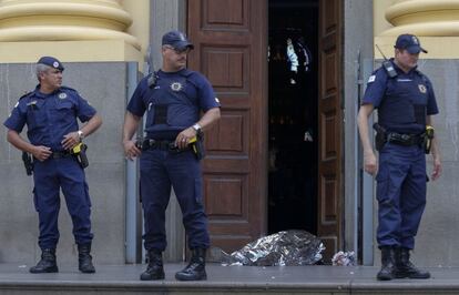 Policías municipales hacen guardia frente al cuerpo de una de las víctimas mortales, en la entrada de la Catedral.  