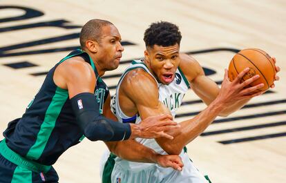 Giannis Antetokounmpo intenta superar a Al Horford. EFE