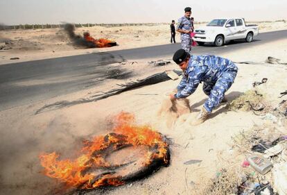 Policías iraquíes lanzan arena para apagar el fuego de un neumático que incendiaron manifestantes frente entrada principal al campo petrolífero de Zubair, cerca de Basora (Irak).