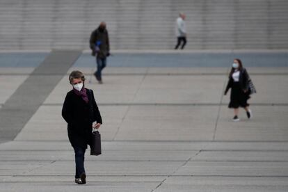 Varias personas con mascarilla caminan por el distrito financiero La Defense, en París.