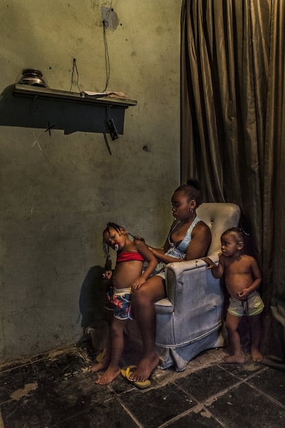 Mãe faz uma trança em uma de suas filhas. Favela Vila do Metrô, Mangueira, Rio de Janeiro.