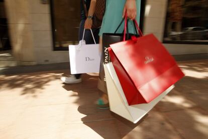 Dos personas con bolsas de marcas de lujo, en Madrid.