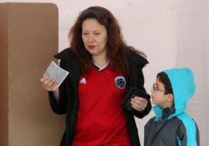 Una mujer, vestida con un jersey del equipo nacional colombiano de fútbol, después de votar este domingo. Le acompaña un niño.