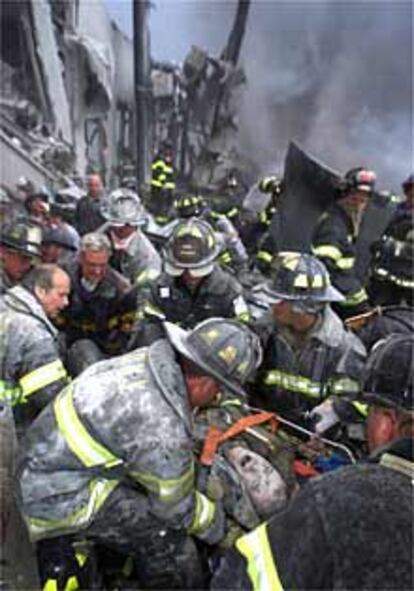 Un bombero es sacado de debajo de los escombros por sus compañeros mientras grita de dolor.