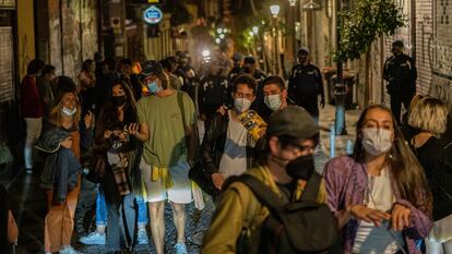 Decenas de personas abandonan una calle del barrio de Malasaña, en Madrid, instadas por la policía.