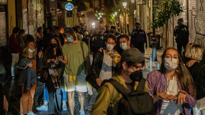 Decenas de personas abandonan una calle del barrio de Malasaña, en Madrid, instadas por la policía.
