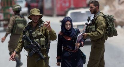 Una mujer palestina pasa junto a soldados israel&iacute;es en Hebr&oacute;n. 