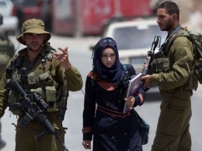 Una mujer palestina pasa junto a soldados israel&iacute;es en Hebr&oacute;n. 