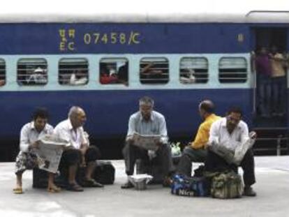 Varios pasajeros leen la prensa para matar el tiempo mientras esperan a que se restablezca hoy el servicio ferroviario en la estación de Amritsar, en el estado de Punjab (India).