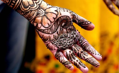 Estudante posa enquanto lhe fazem uma tatuagem de hena em Bhopal, na Índia.