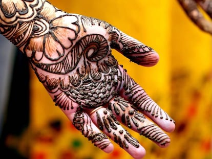 Estudante posa enquanto lhe fazem uma tatuagem de hena em Bhopal, na  &Iacute;ndia.