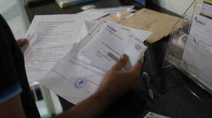 Un ciudadano presenta en una oficina de Correos la documentación con sus papeletas para votar por correo en las elecciones del 26- J.