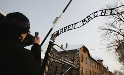Una visitante fotografía la réplica del cartel original colocada ayer en la entrada de Auschwitz.