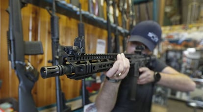 Un hombre sostiene un AR-15 en una tienda de armas.