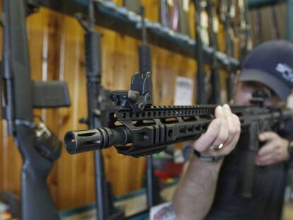 Un hombre sostiene un AR-15 en una tienda de armas.