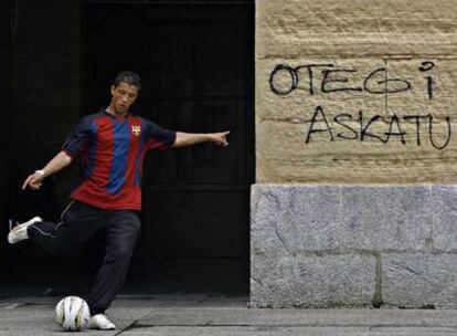 Un joven juega al fútbol junto a una pintada que pide la libertad de Otegi en San Sebastián.