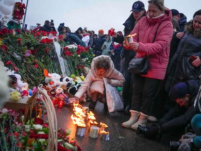 Una mujer enciende este sábado velas junto a la sala de conciertos Crocus City Hall, al noroeste de Moscú, lugar del atentado del Estado Islámico.