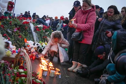 Una mujer enciende este sábado velas junto a la sala de conciertos Crocus City Hall, al noroeste de Moscú, lugar del atentado del Estado Islámico.