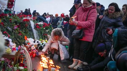 Una mujer enciende este sábado velas junto a la sala de conciertos Crocus City Hall, al noroeste de Moscú, lugar del atentado del Estado Islámico.