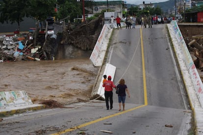 Las personas cruzan un puente colapsado en Coyuca de Benítez, Estado de Guerrero, México.