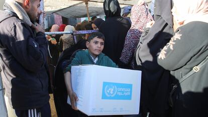 Un niño sostiene una caja de la UNRWA, este martes en Jan Yunis. 