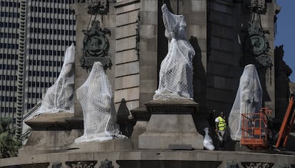 Cuatro de las seis esculturas de la base del monumento de Colón envueltas, por protección, como lo habría hecho Christo.