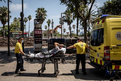 Dos sanitarios subían a un paciente a una ambulancia durante la ola de calor, en Barcelona, el lunes.
