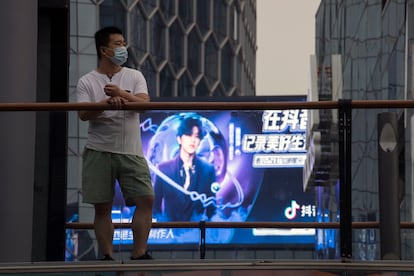 Un hombre enfundado en una mascarilla ante una publicidad de Douyin (la app hermana de TikTok en China) en Pekín el 30 de agosto.