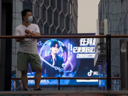 Un hombre enfundado en una mascarilla ante una publicidad de Douyin (la app hermana de TikTok en China) en Pekín el 30 de agosto.