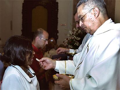El ex pastor anglicano Evans David Gliwitzki da la comunión a su esposa, Patricia, durante su ordenación.