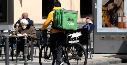 Un repartidor de Uber Eats espera junto a un establecimiento de hostelería en Madrid.