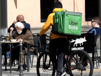 Un repartidor de Uber Eats espera junto a un establecimiento de hostelería en Madrid.