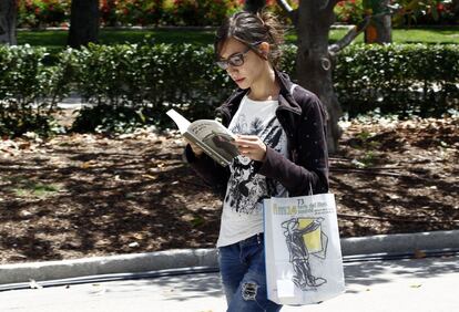 Una joven lee un libro tras visitar la Feria del Libro.