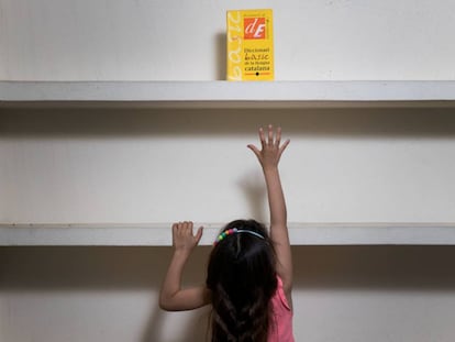 Una nena intenta agafar un diccionari de llengua catalana.