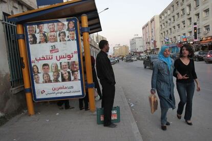 Dos jóvenes pasean junto a un cartel que reza "Túnez vota".