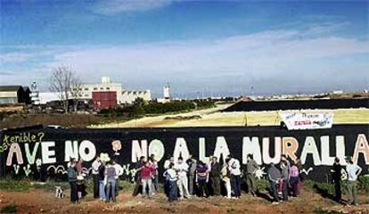 Los miembros de la coordinadora ante el mural de 50 metros, la misma anchura que la plataforma elevada sobre la que discurrirá el AVE.