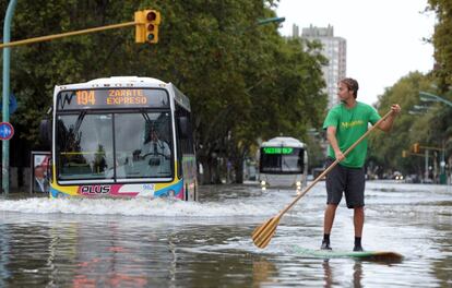 Un hombre encima de una tabla de surf en una calle de Buenos Aires (Argentina) tras las intensas lluvias caídas.