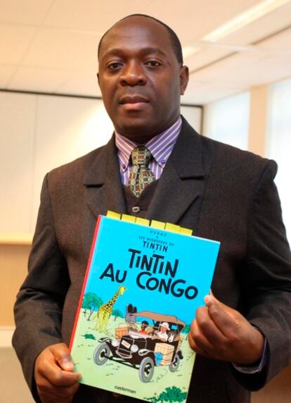 El congoleño residente en Bélgica Mbutu Mondondo Bienvenue sostiene una copia del cómic 'Tintín en el Congo' a su llegada a un juicio en Bruselas.