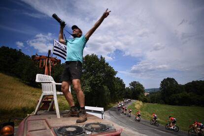 Un aficionado al ciclismo anima la competencia sobido en el techo de un coche, durante la undécima etapa de la 106ª edición del Tour de Francia entre Albi y Toulouse, el 17 de julio de 2019.