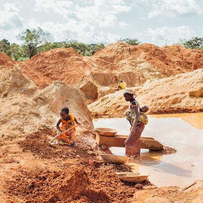 Una madre con su bebé en la espalda y su hija mayor trabajan buscando oro en una mina ilegal en Beke Route, este de Camerún