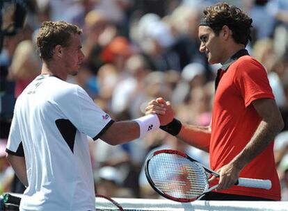 Federer, de rojo, y Hewitt se dan la mano tras el partido.