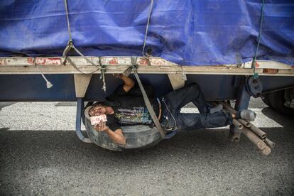 Un migrante que viaja en la parte inferior de un camión muestra un billete, en una carretera cerca de Jocotán (Guatemala).