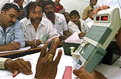 Interventores de los partidos miran una máquina electrónica de recuento de votos en la ciudad sureña de Bangalore.