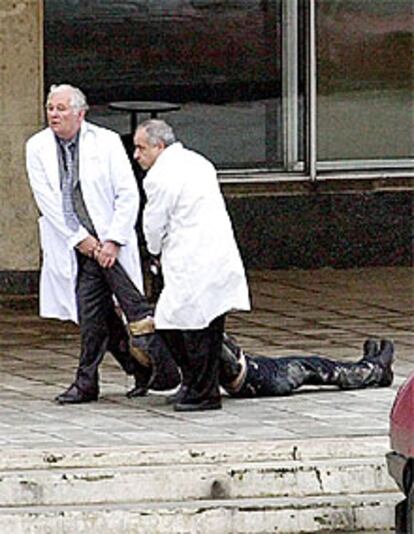 Dos sanitarios arrastran el cadáver de una de las rehenes del <i>comando</i> checheno frente al teatro de Moscú.