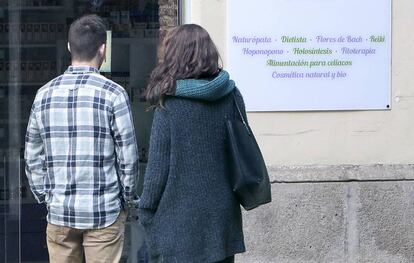 Una pareja, frente a un centro de terapias alternativas en Valencia.