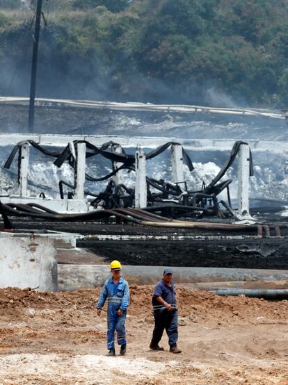 Dos empleados públicos inspeccionan la zona del incendio luego de que este fuera sofocado el 10 de agosto de 2022.
